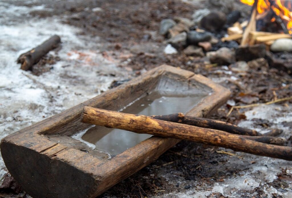 A hollowed out log with sap in it next to a fire.