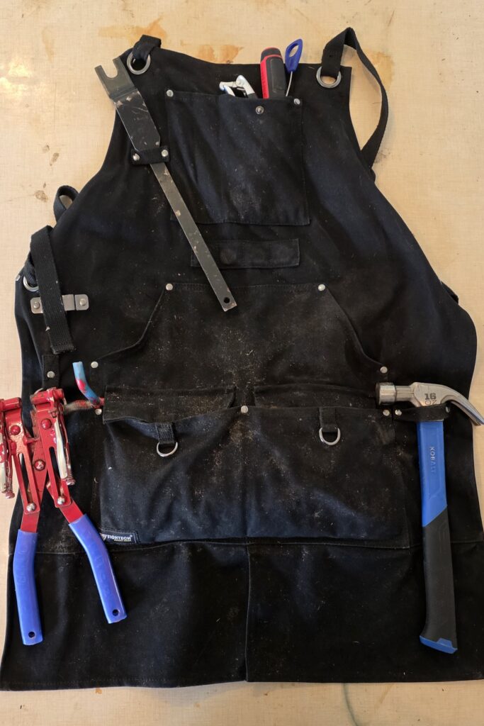 A work apron filled with maple sugaring equipment.