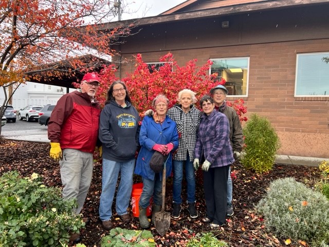 A group of master gardeners in front of a bush in fall colors.