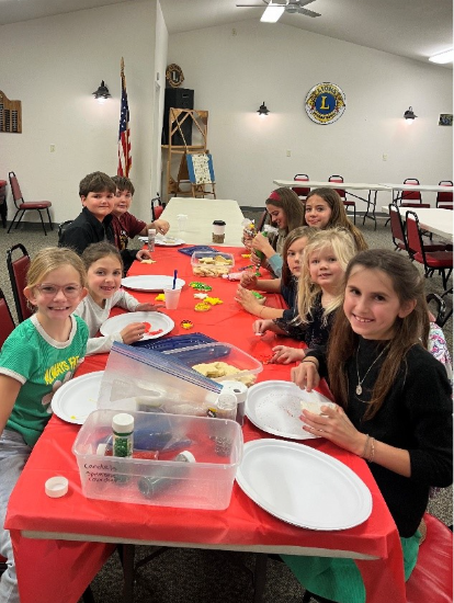 Nine 4-H club members sitting around a table with cookie decorating supplies