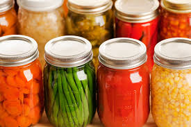 Glass jars filled with home-canned vegetables such as carrots, beans, and corn.