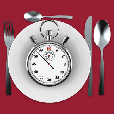Stopwatch placed on a plate with fork, knife, and spoon on a red background.