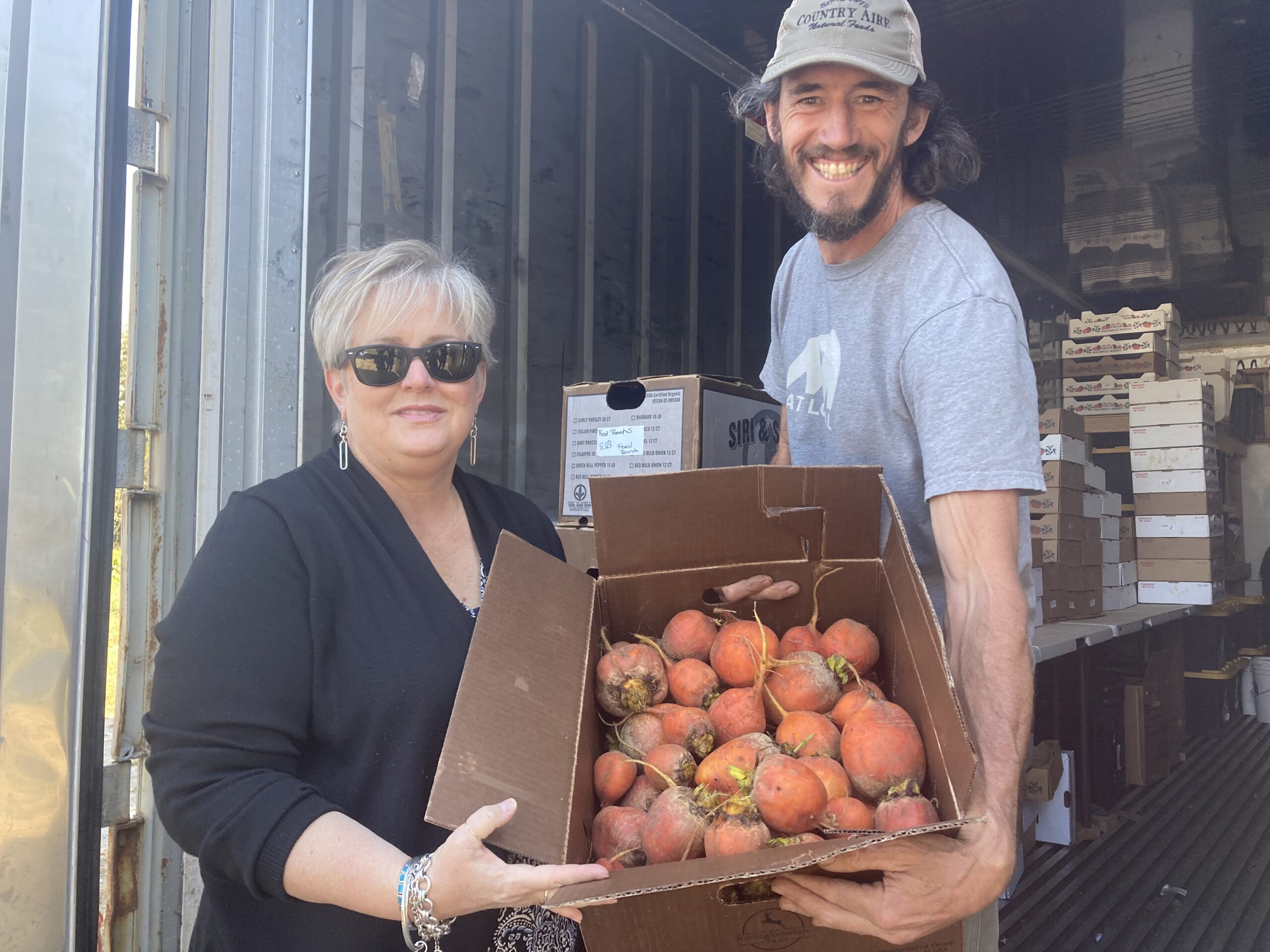 Farmer Scott Chichester loading Sequim Food Bank Director's vehicle with cases of fresh produce