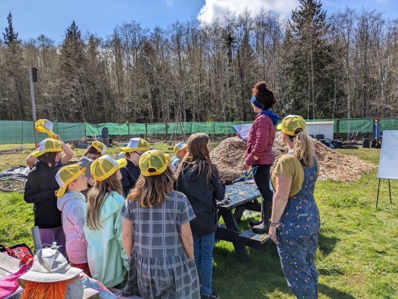 A group of students and a teacher standing outside in a field.
