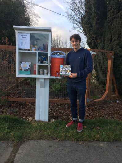 Man with book stands by little free pantry