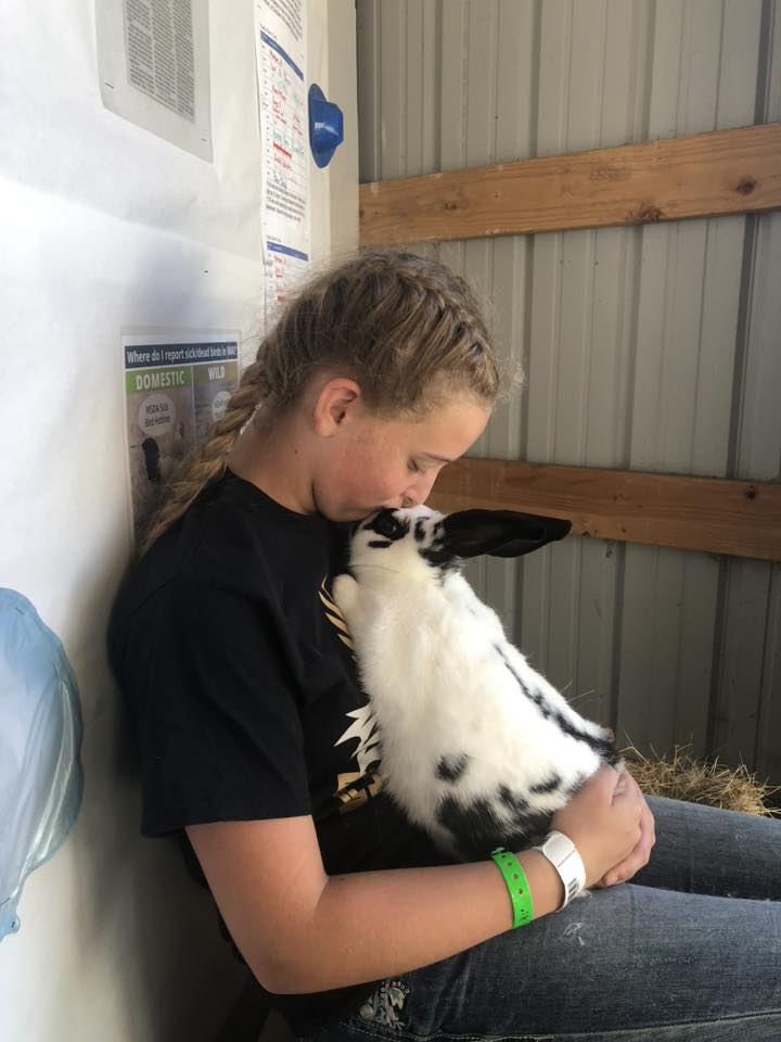 Teen girl holding her pet rabbit and kissing it on the forehead.