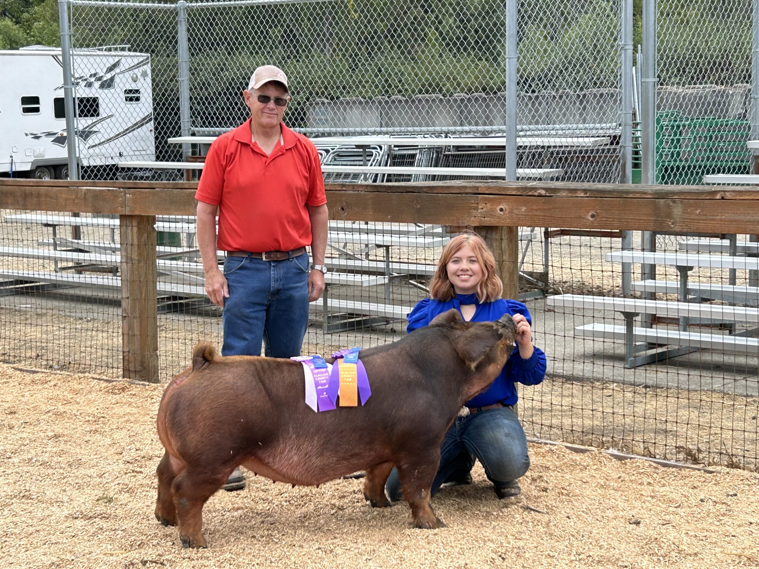Teen girl posing with prize winning pig and pig judge at the county fair