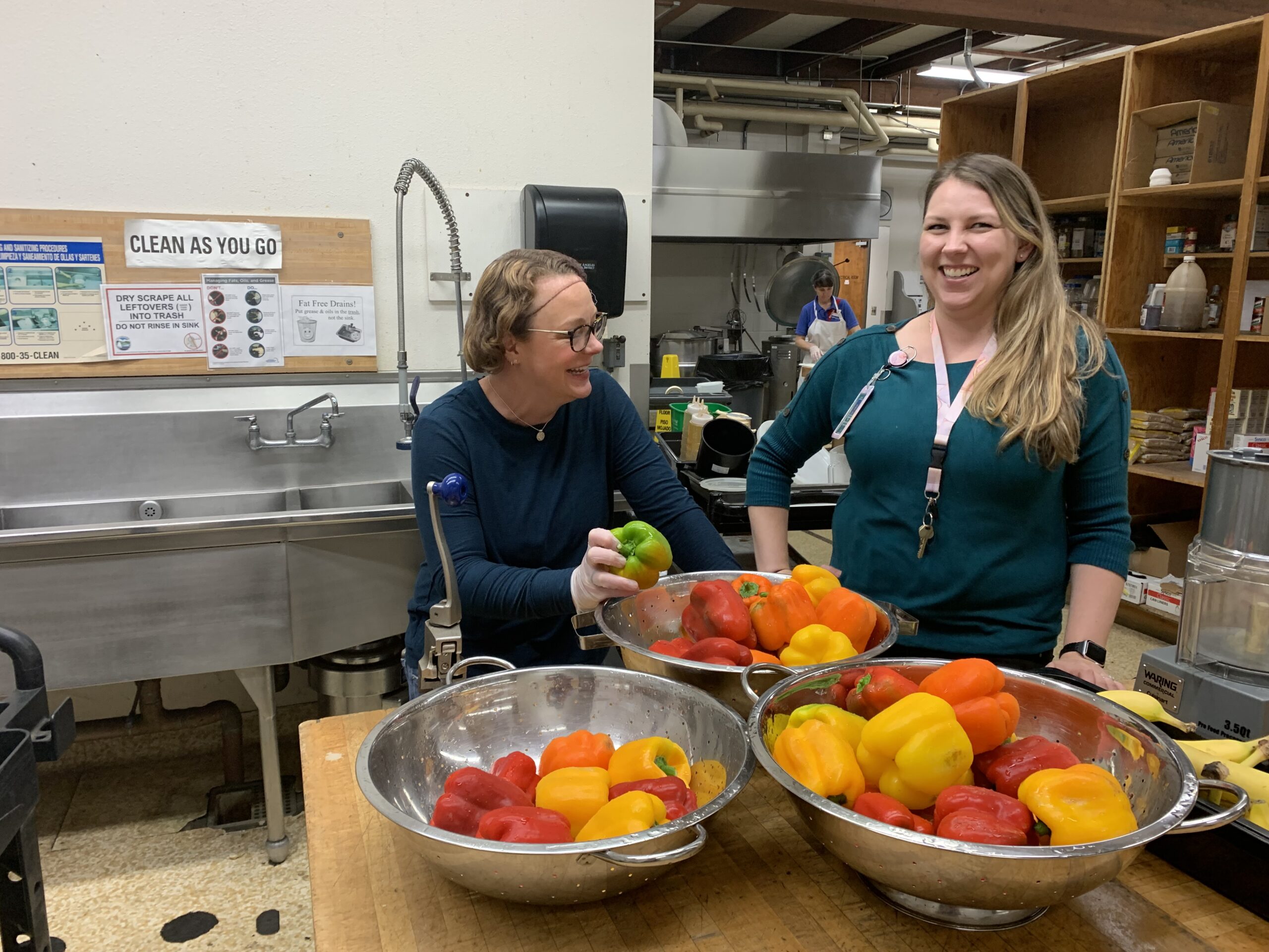 Farm to School program image: Women talking in kitchen with bell peppers