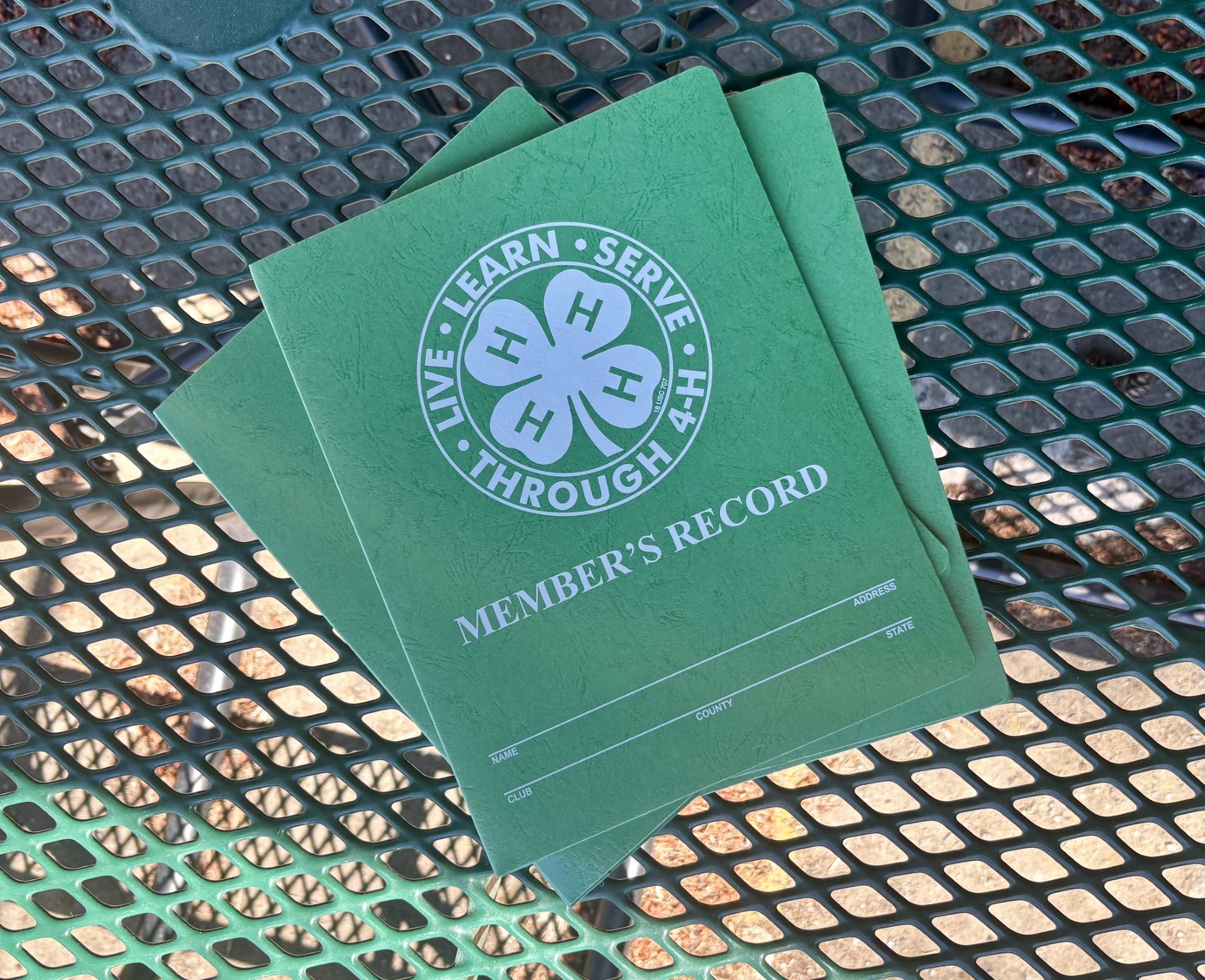 a stack of 4-h record books piled on a table
