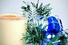 glass of eggnog next to holiday decorations