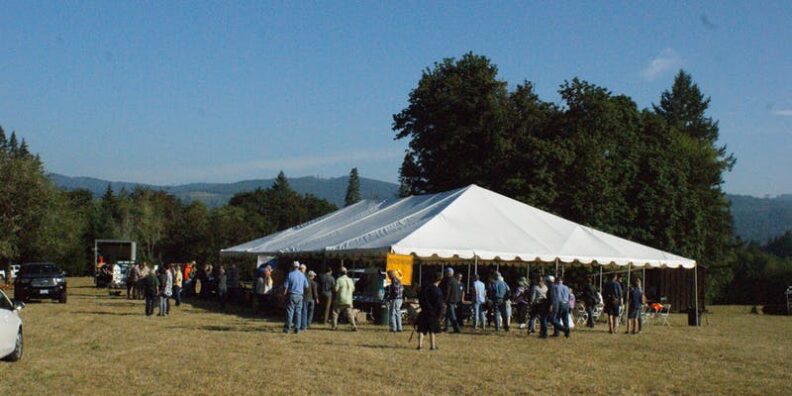 people crowded under tent in open field for forestry field day presentation