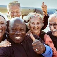 folks on a beach smiling, giving a "thumbs up"