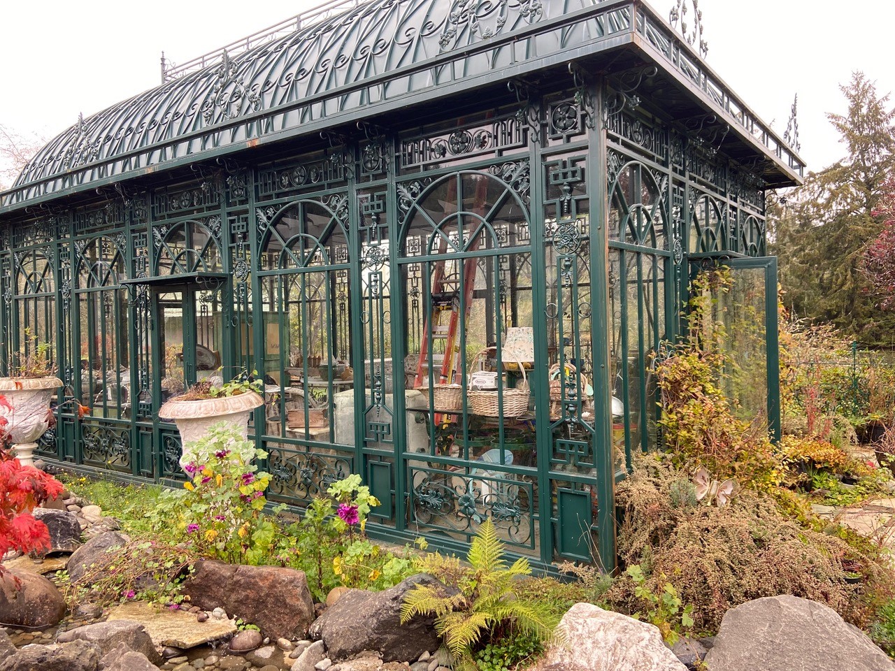 Green metal greenhouse w/urns outside at 2025 Annual Garden Tour