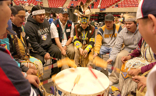 Several people surrounding Pow-wow drums.