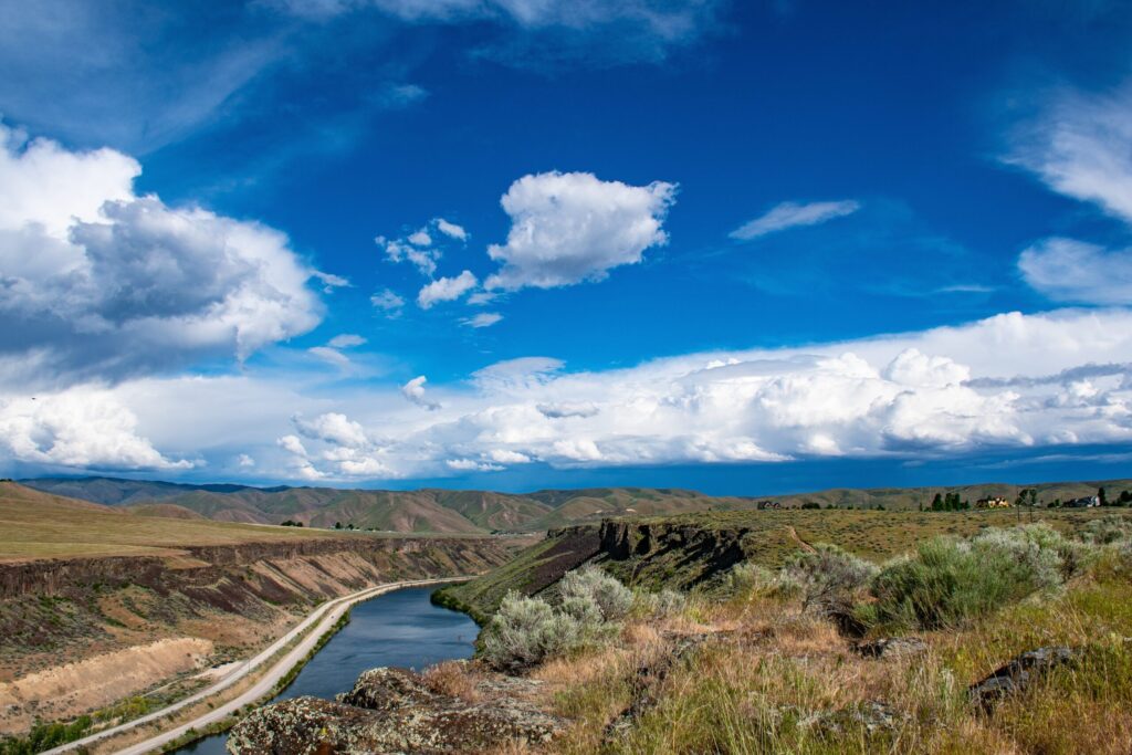 Blue sky with some clouds. River cuts through the land.