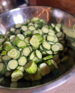 photo of a large bowl of cucumber slices, preparing for making pickles