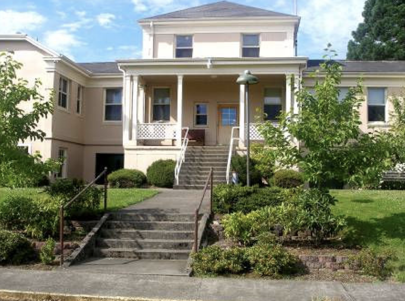 Front entrance of the Clark County Extension building with stairs, porch, and landscaped greenery