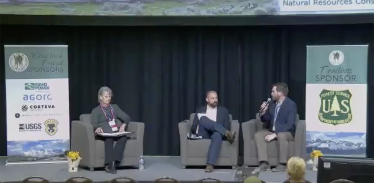 Three people sitting in chairs on a stage for a panel discussion.