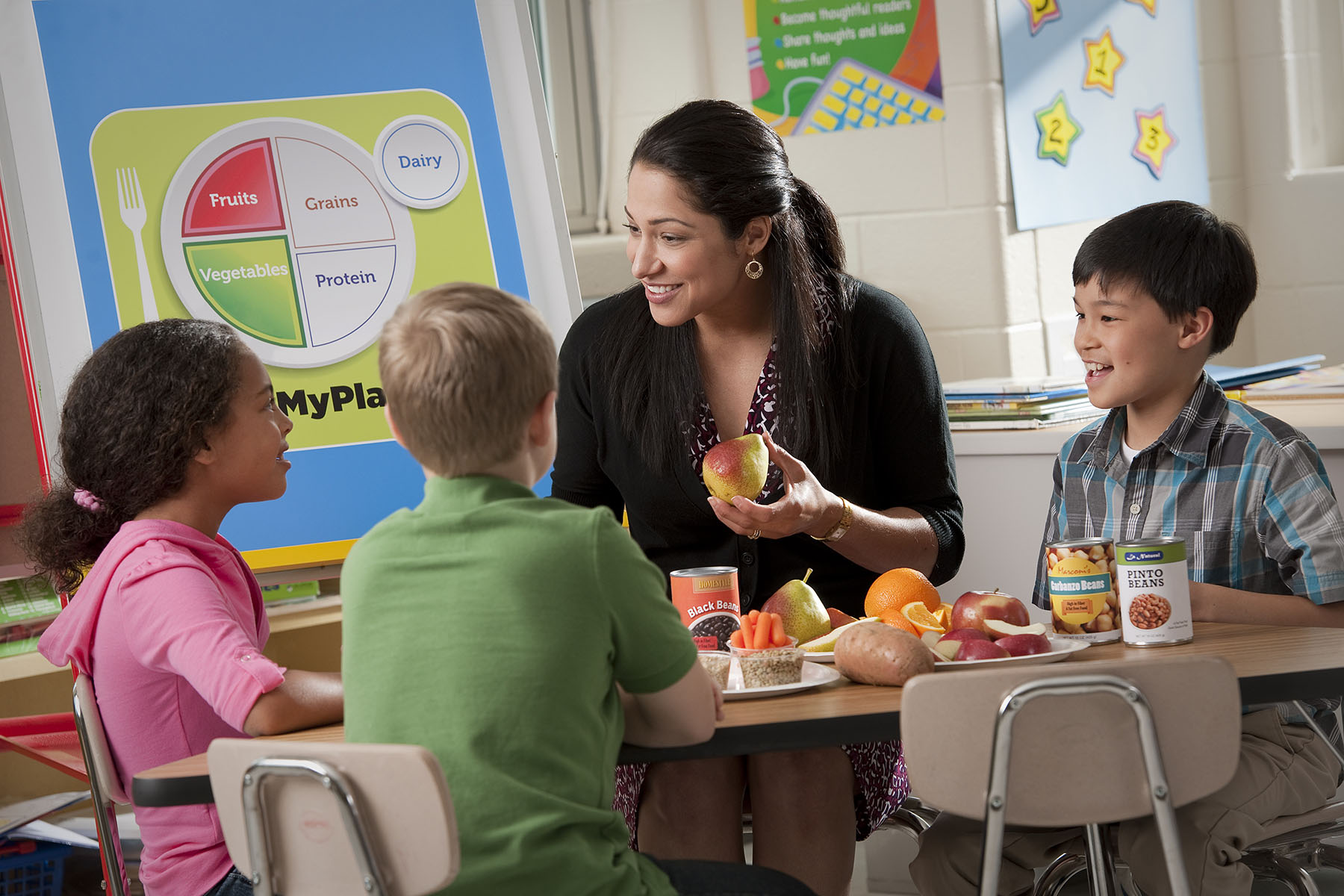 Teacher teaching three children about nutrition.