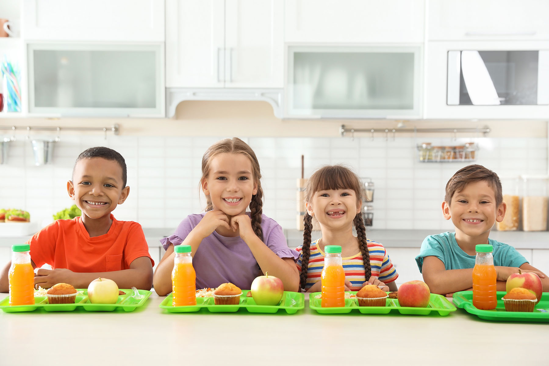 Smiling children sitting at table eating healthy food