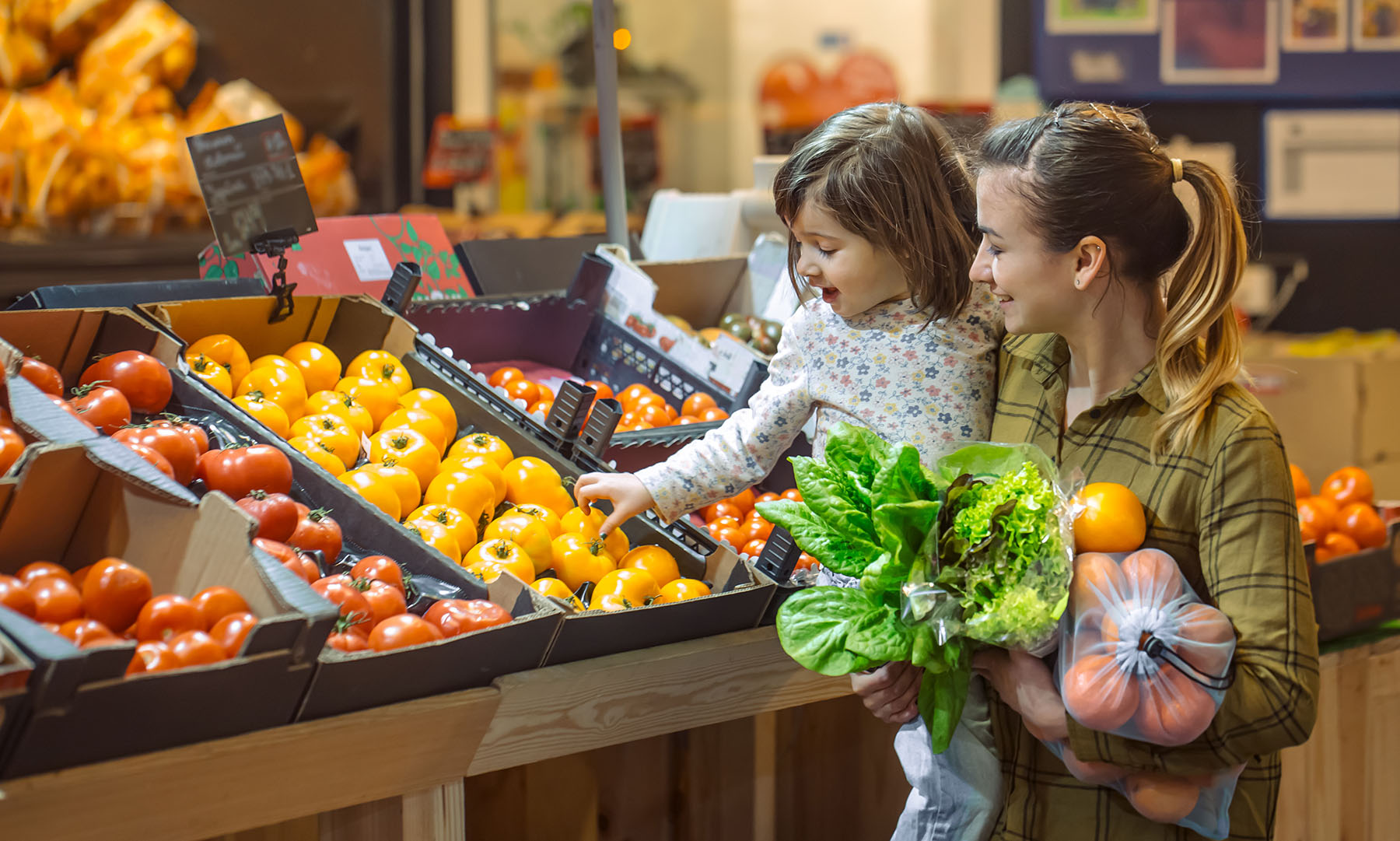 Young mom and daughter getting produce at store