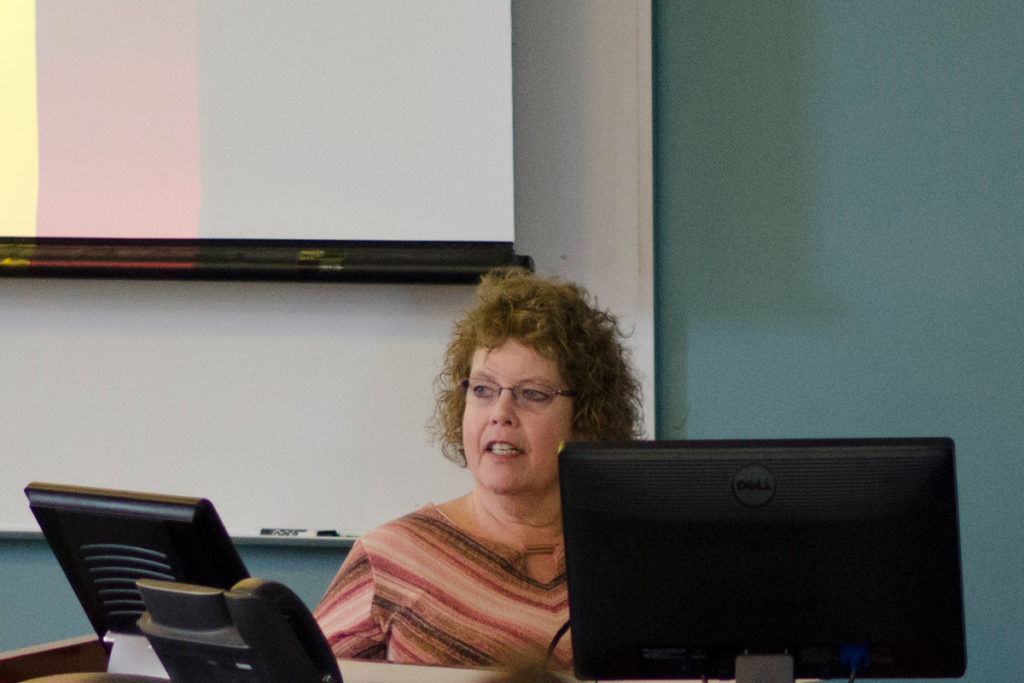 Professor Naomi Lungstrom at her desk speaking to a classroom.