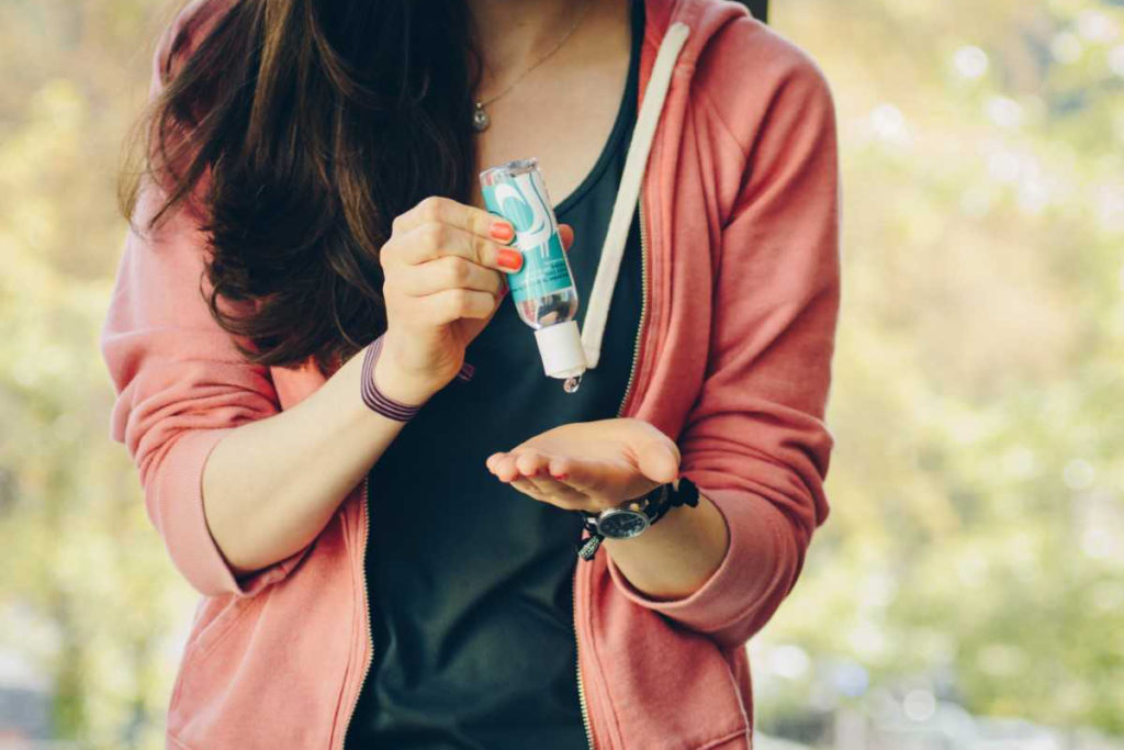 Student squeezing hand sanitizer from a bottle into her hand