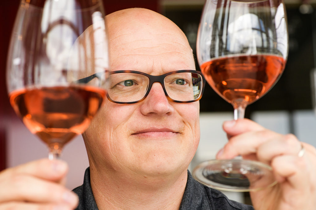Jim Harbertson inspects two glasses of rosé wine.