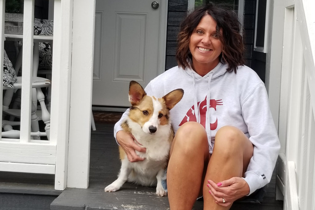 A closeup of Kristy Fiorini and Murray sitting on steps to a porch.