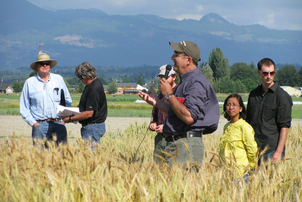 A speaker addresses people in wheat field.