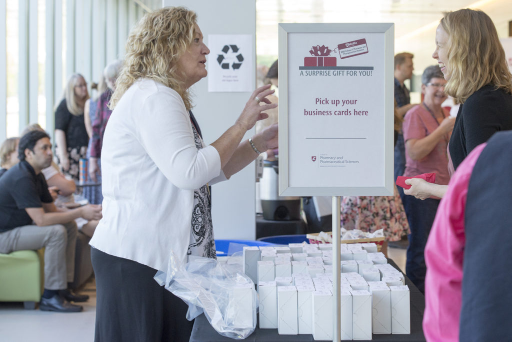 Two women standing beside table with boxes of business cards.