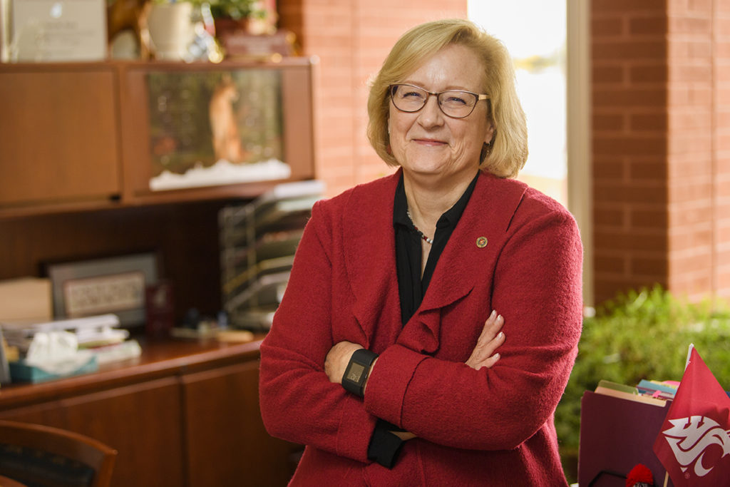 Joan King leaning against her office desk.