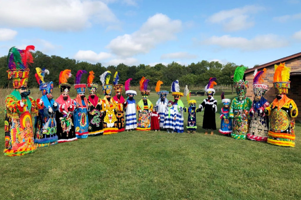 Costumed Chinelos dancers standing together outside.