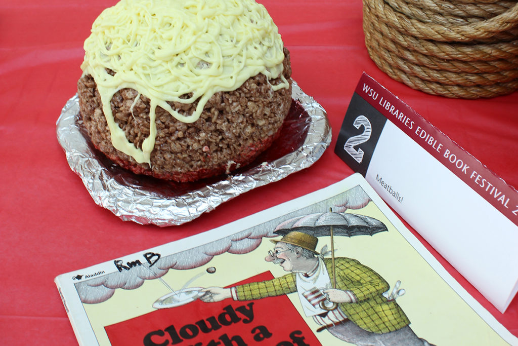 Giant meatball and pasta next to 'Cloudy with a Chance of Meatballs' children's book.