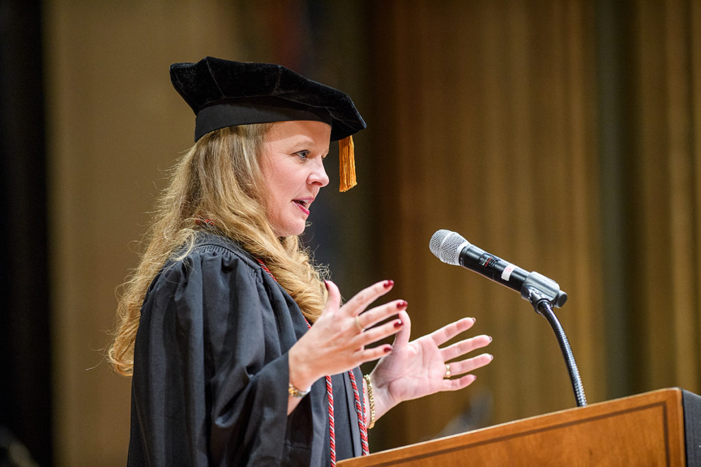 Merrie Kay Alzola standing at podium giving commencement address.