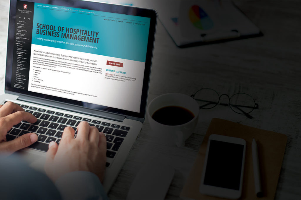 A photograph of a laptop screen with the School of hospitality business management web page