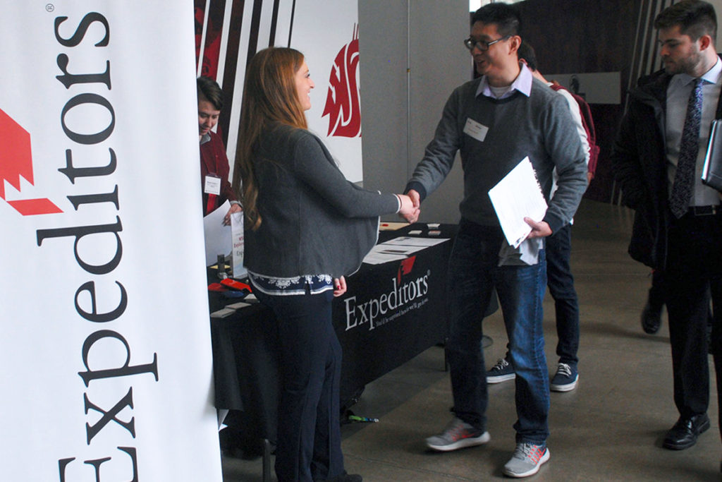 Two people shake hands during a career expo.