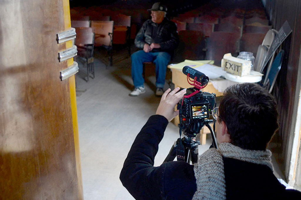 A student filming with a camera and tripod.