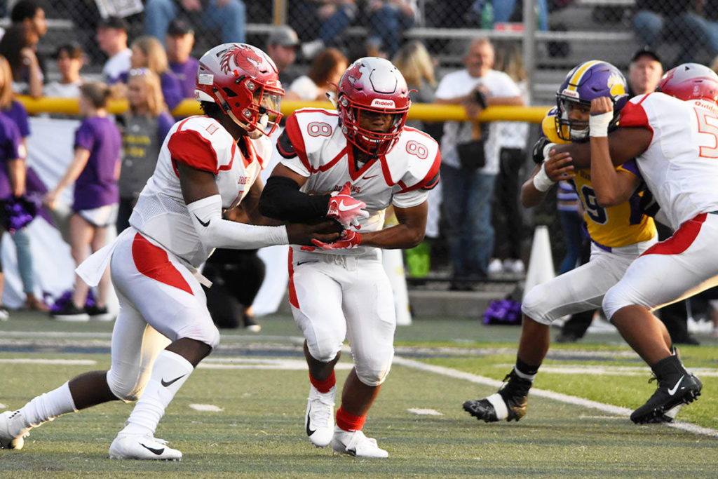 A football quarterback hands the ball off to a running back.