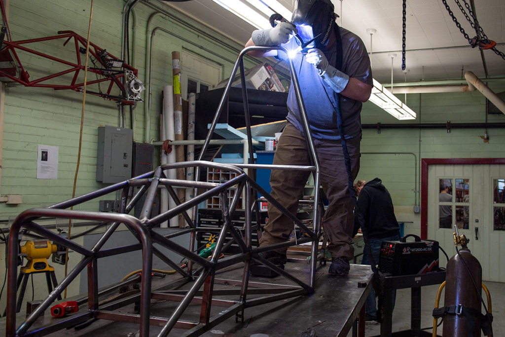 A student uses a welding tool on the Wazzu Racing team's car.