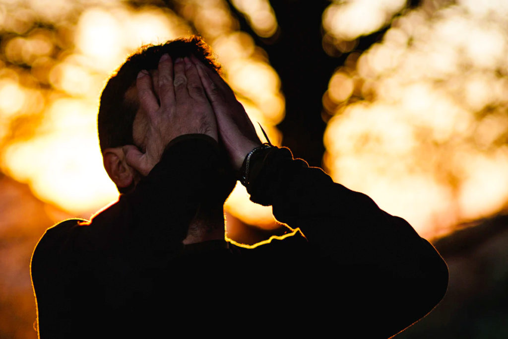Closeup of man with hands placed over his face.