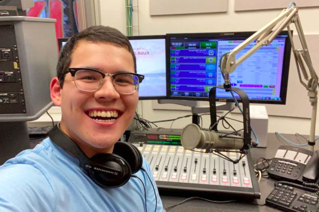 Albert James sits in a studio with several pieces of broadcast equipment.