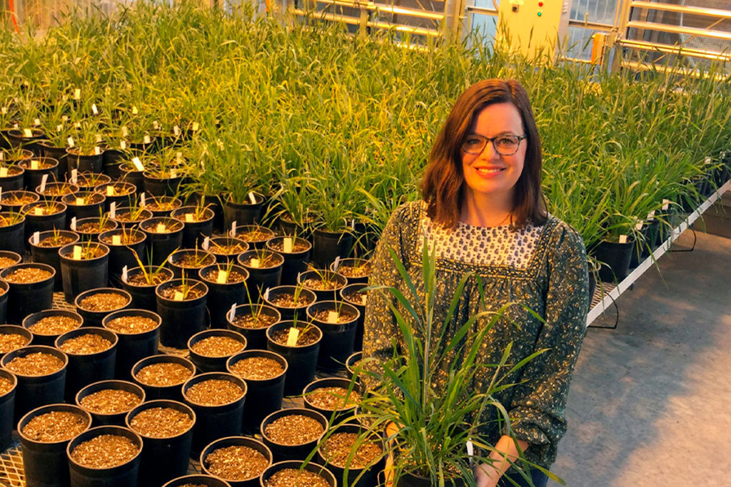 Sanguinet holding a plant inside a greenhouse.