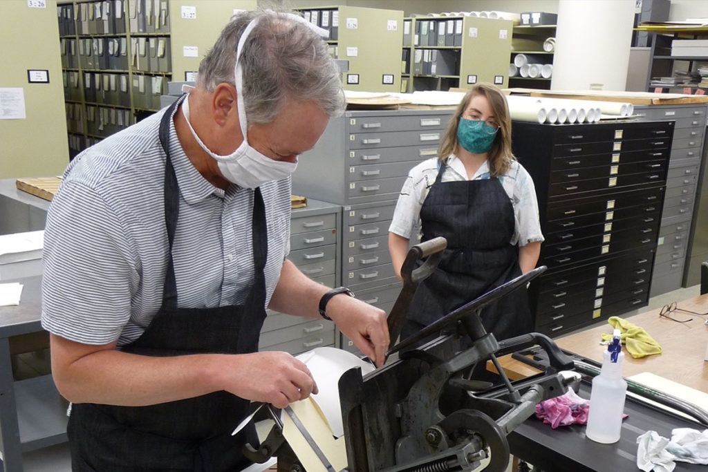 Two people work at a letterpress.