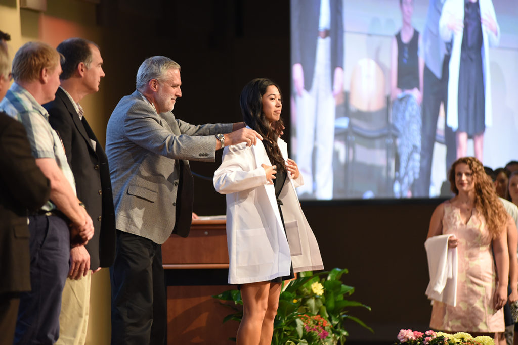 A veterinary medicine graduate receives her white coat