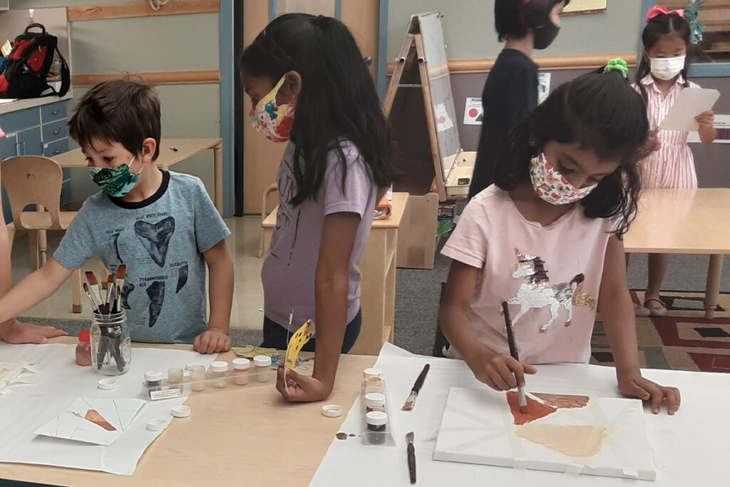 Children painting art projects in a classroom.