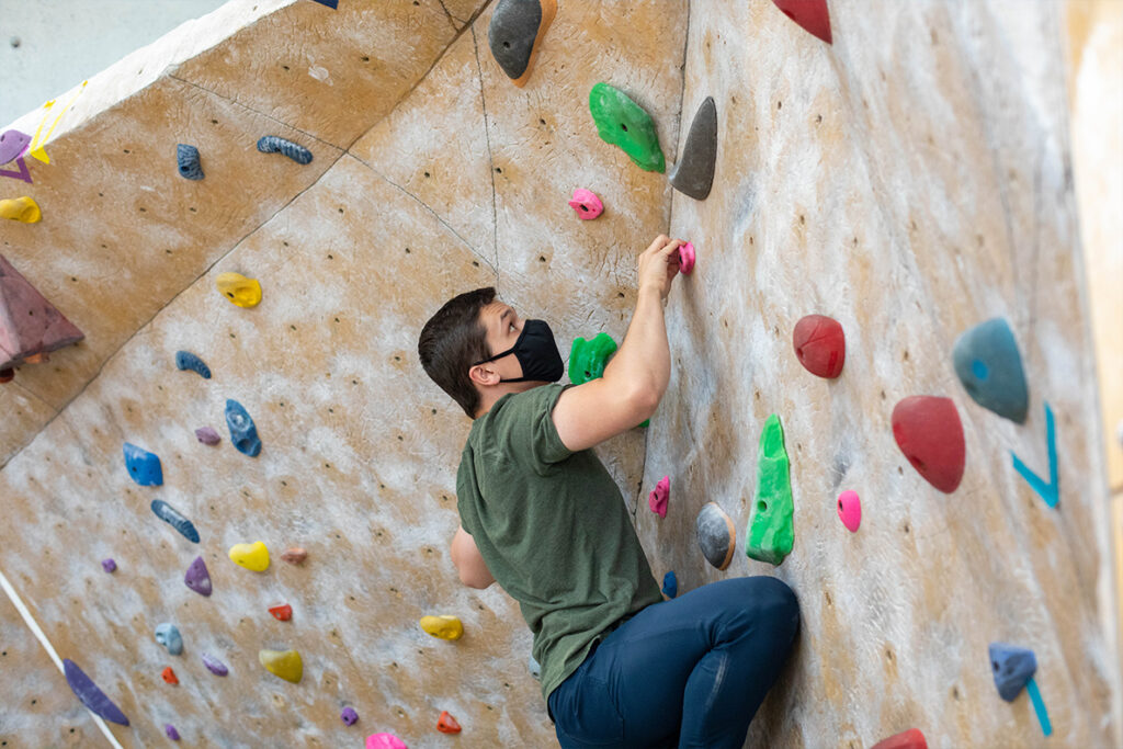 A student climbs on the climbing wall at the UREC center.