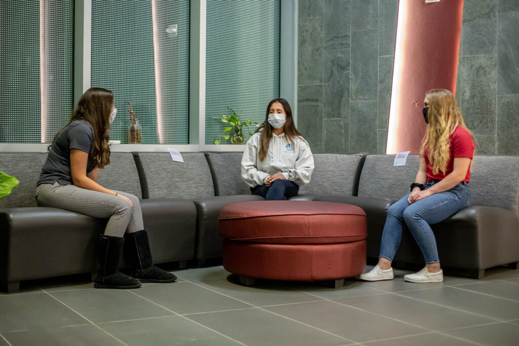 Three students talk around a table