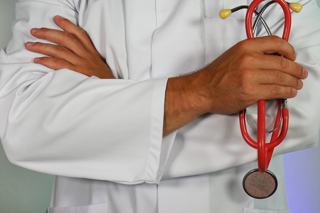 Closeup of a doctor's arms crossed while holding a stethoscope.