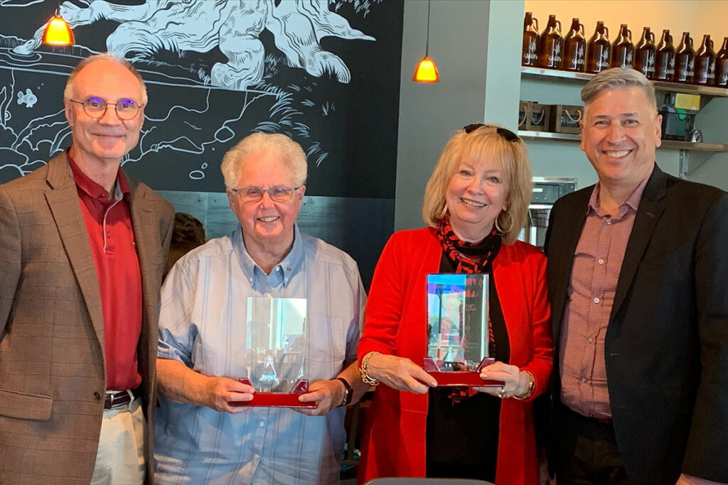 Two women holding awards next to two men in sports coats